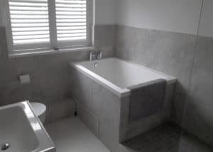 The Calyx soaking tub, set into a grey tiled surround.